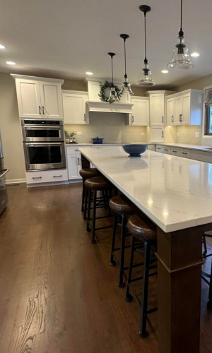 Kitchen wall with white baseboards and wooden flooring.